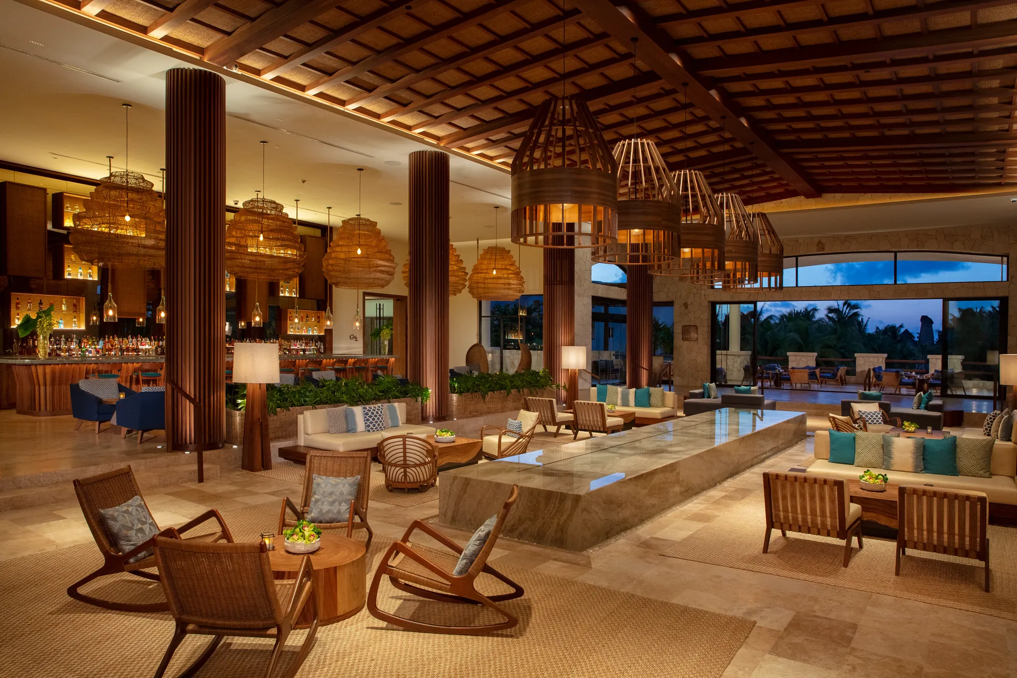 Elegant lobby lounge with woven pendant lights and bar seating at Secrets Maroma Beach Riviera Cancun.