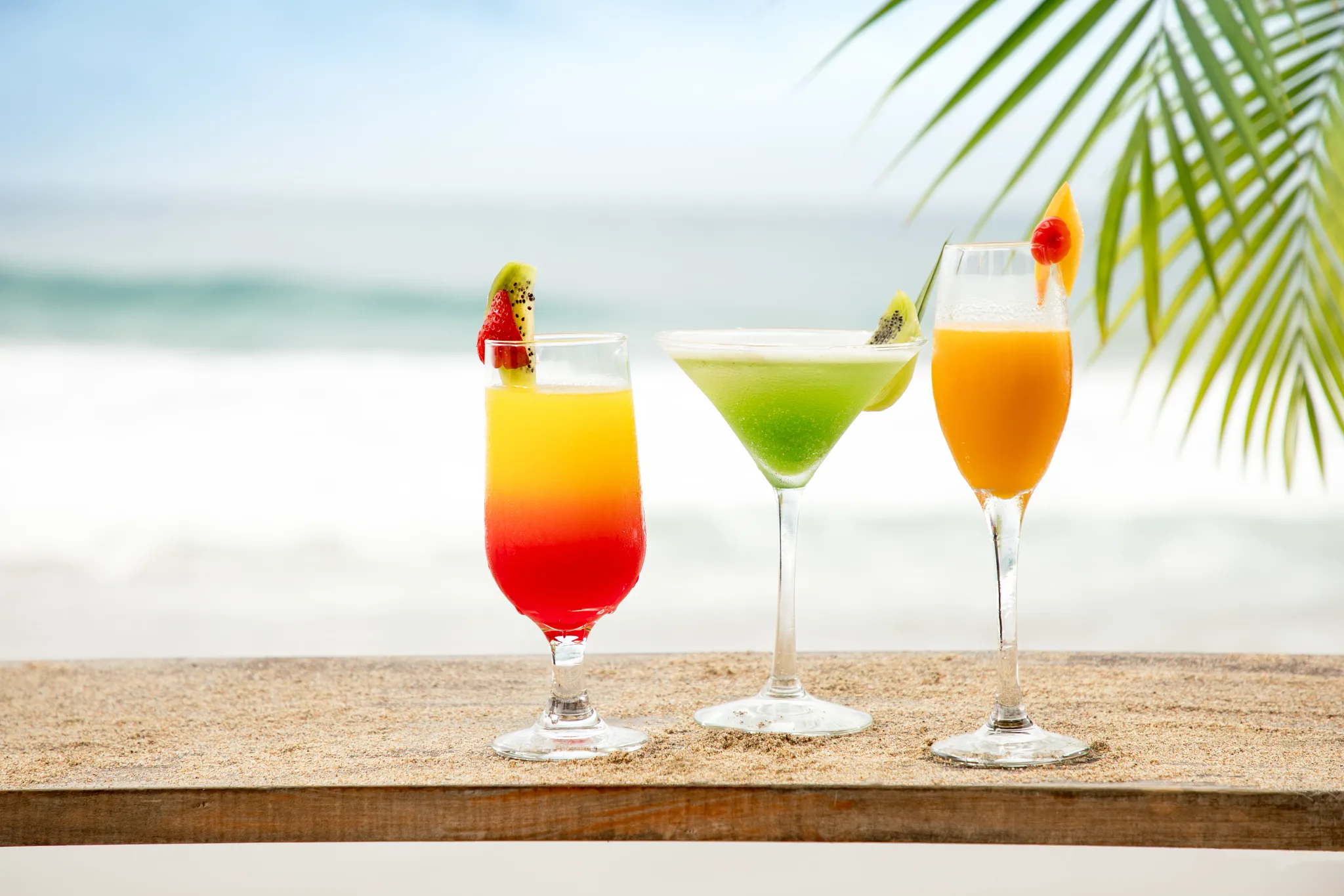 Colorful tropical cocktails served at Palapa Beach Bar at Secrets Maroma Beach Riviera Cancun overlooking the ocean.