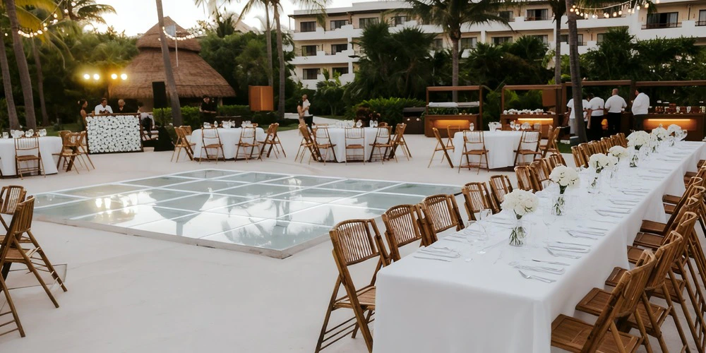 Seaside Terrace Venue at Secrets Maroma Beach featuring an elegant outdoor reception with long banquet tables, glass dance floor, palm trees, and tropical resort backdrop.
