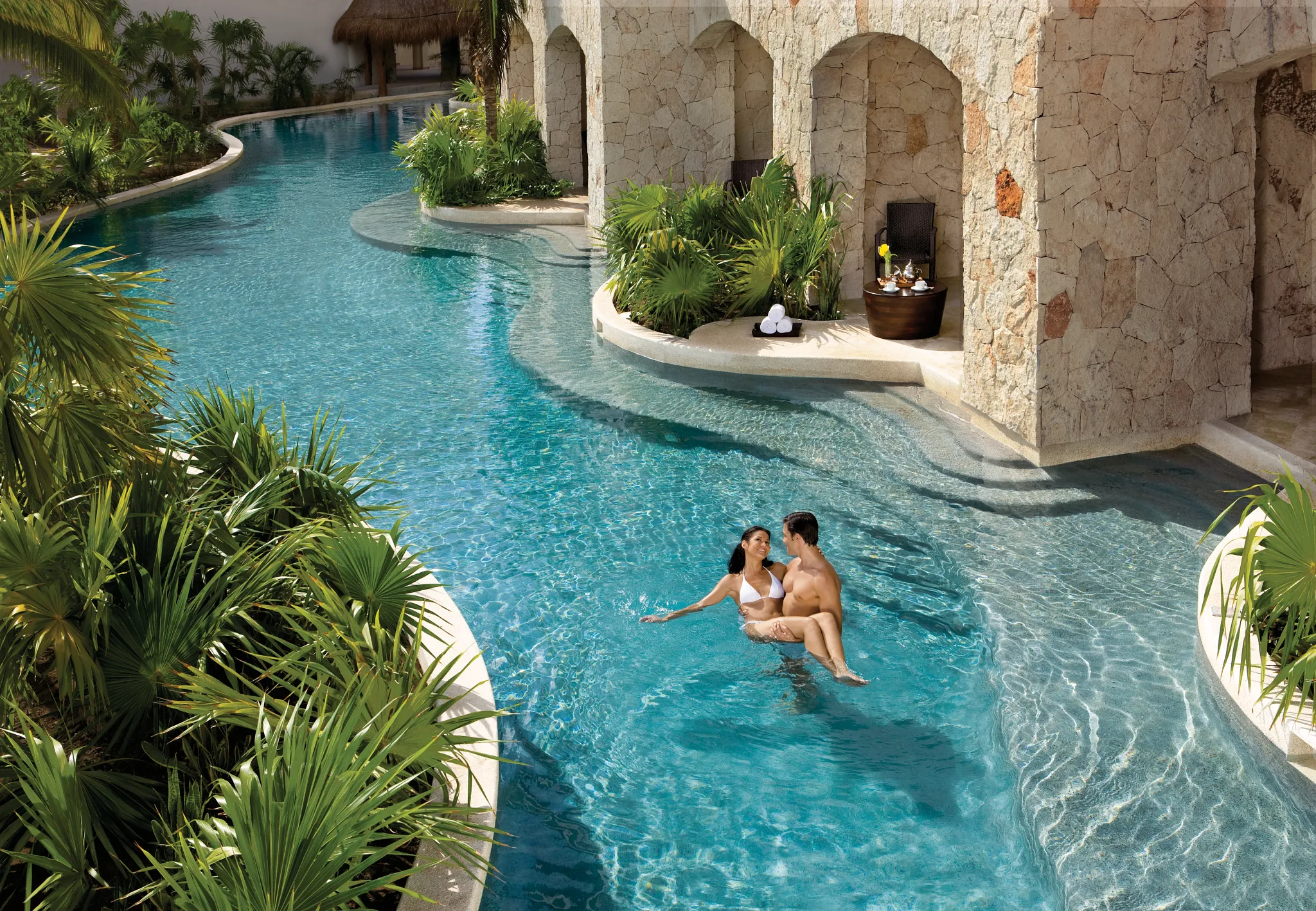 Couple enjoying a private swim-out suite pool at Secrets Maroma Beach Riviera Cancun surrounded by tropical landscaping.